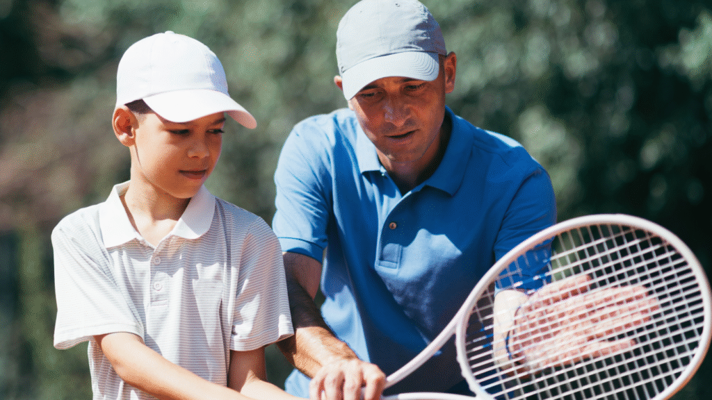 Profesor de tenis enseñando a alumno, simbolizando guía en el camino hacia el autoconocimiento y la transformación personal.