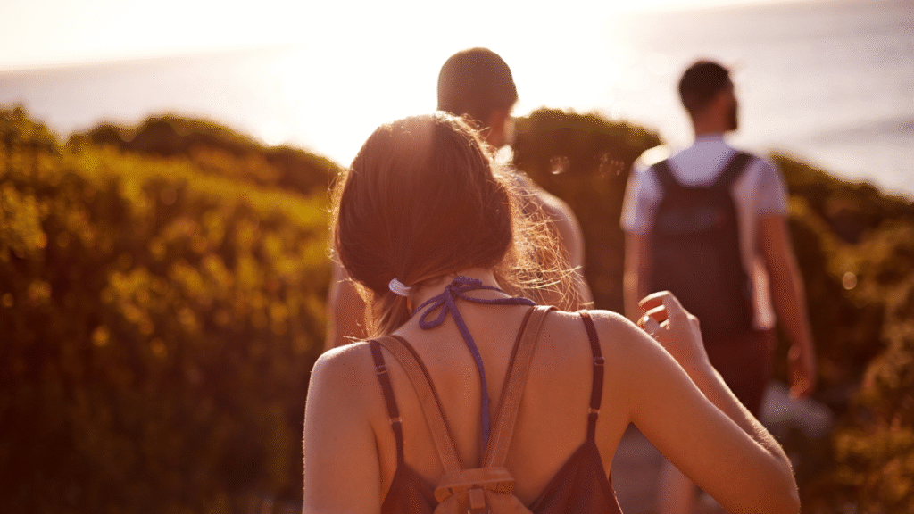 Mujer caminando por un sendero en una tarde soleada, simbolizando el camino hacia una vida más consciente y con propósito.